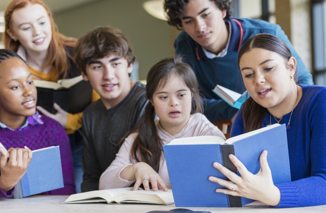 Students surrounding another individual reading a book