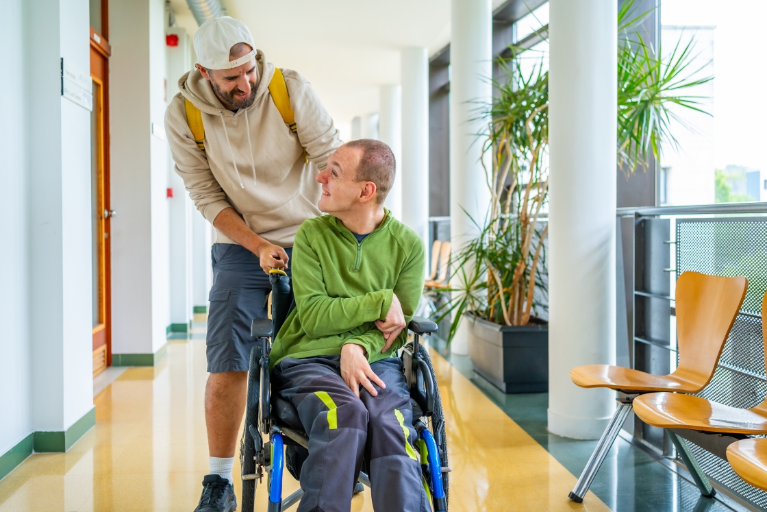 Man pushing another man in a wheelchair